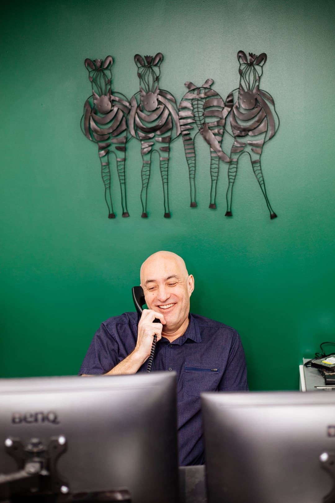 Roy Castleman working at his desk, phone in hand, smiling